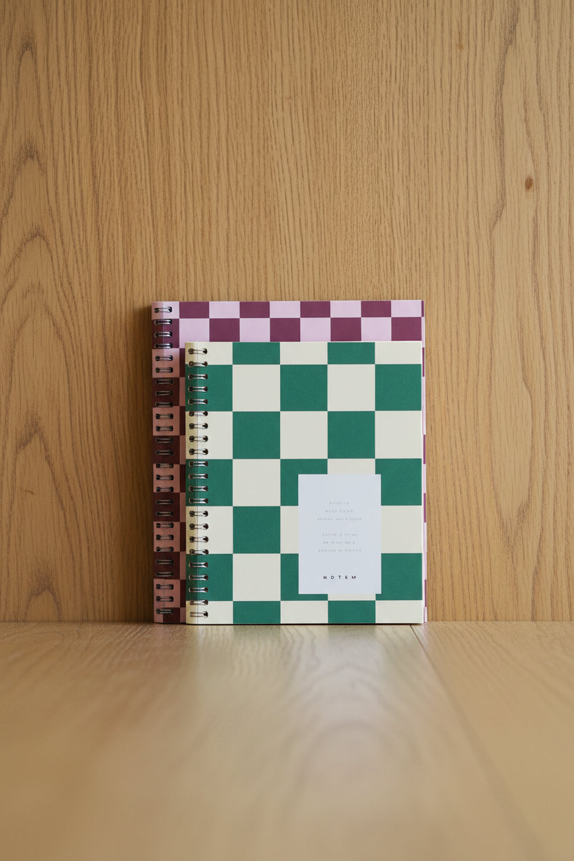 Two notebooks with checkered patterns on a wooden surface