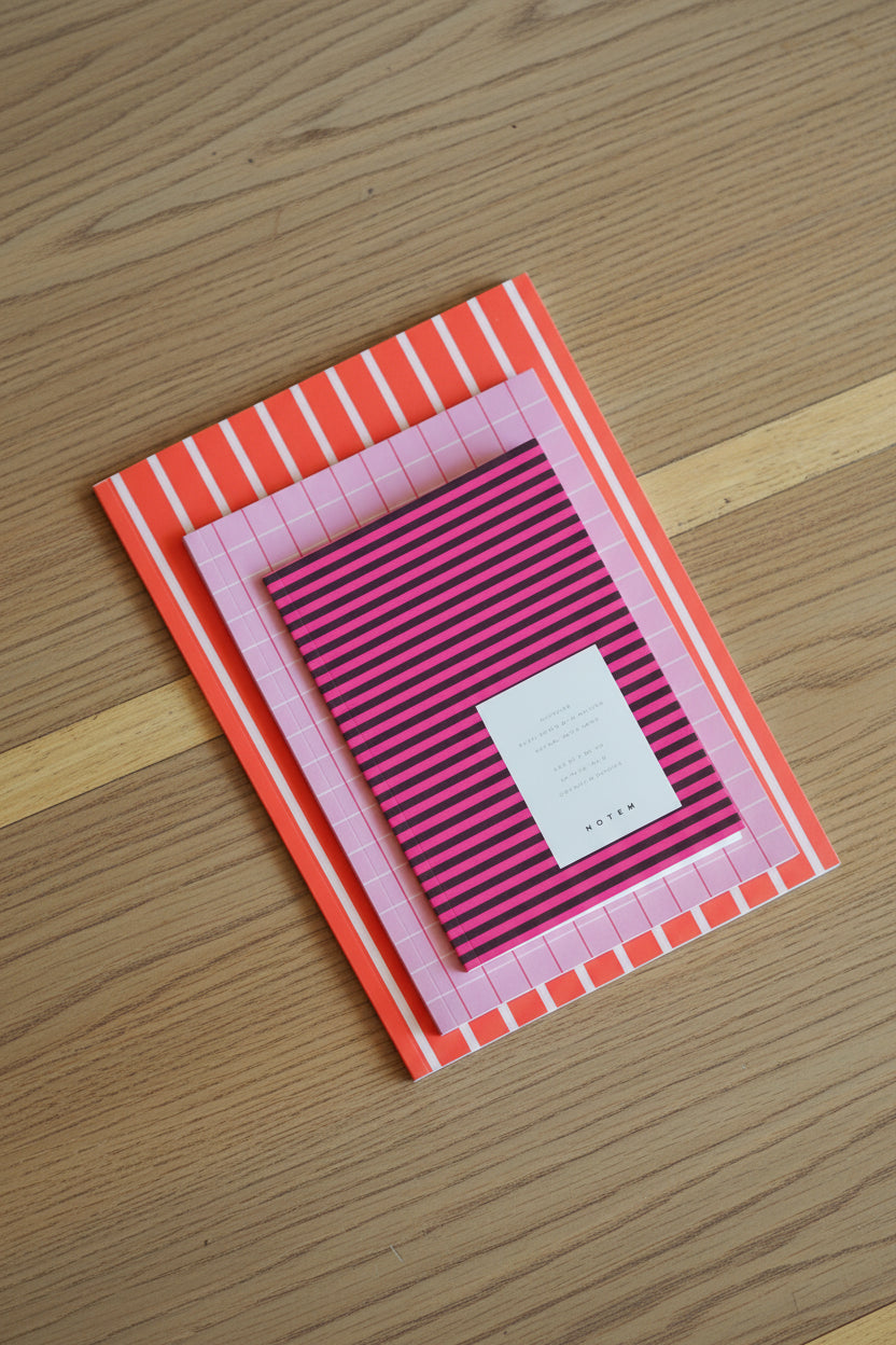Pink and orange striped notebook on a wooden surface